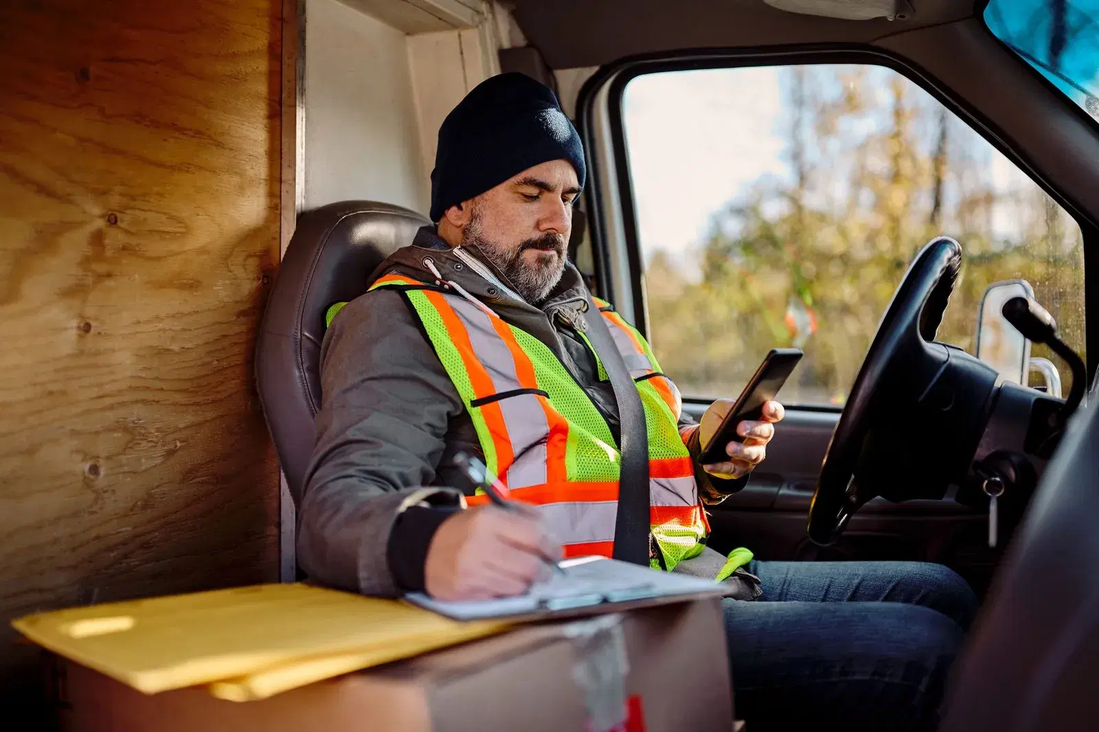 Driver sitting in his cab filling out paperwork with his phone in hand